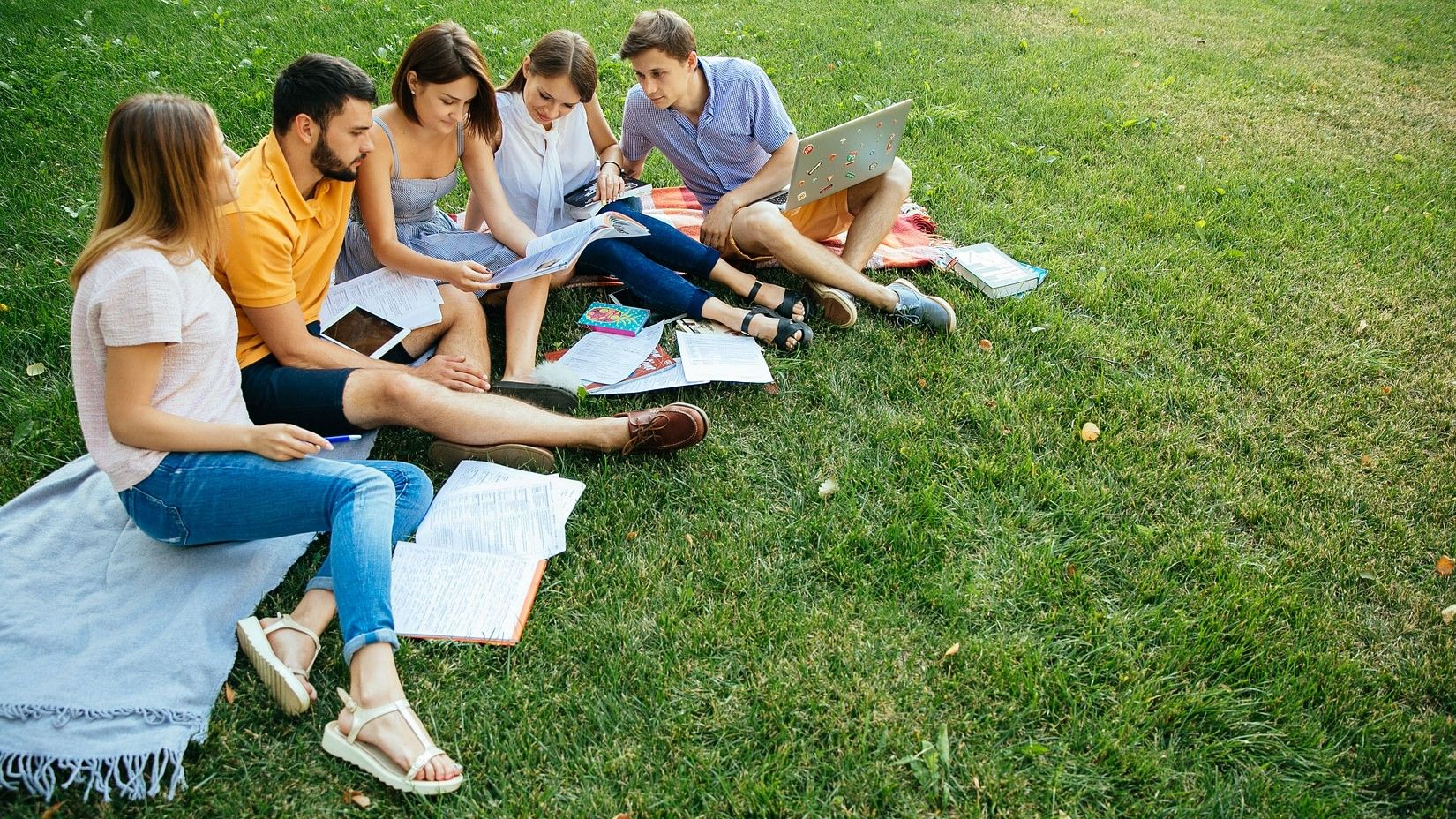 Group of kids reading book in garden