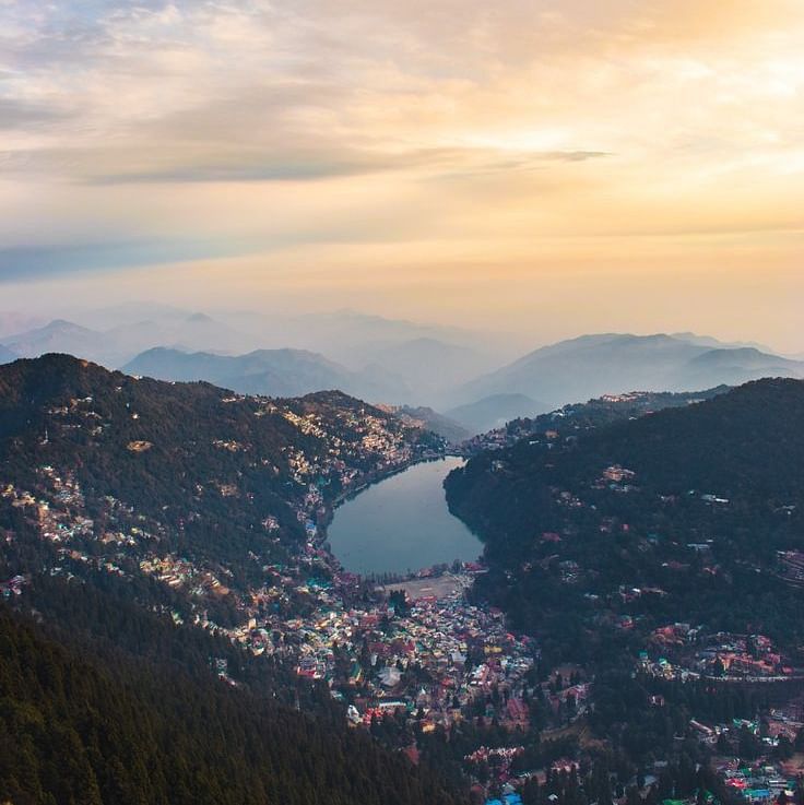 An overview of Nainital with a serene lake and sunlit sky in view.
