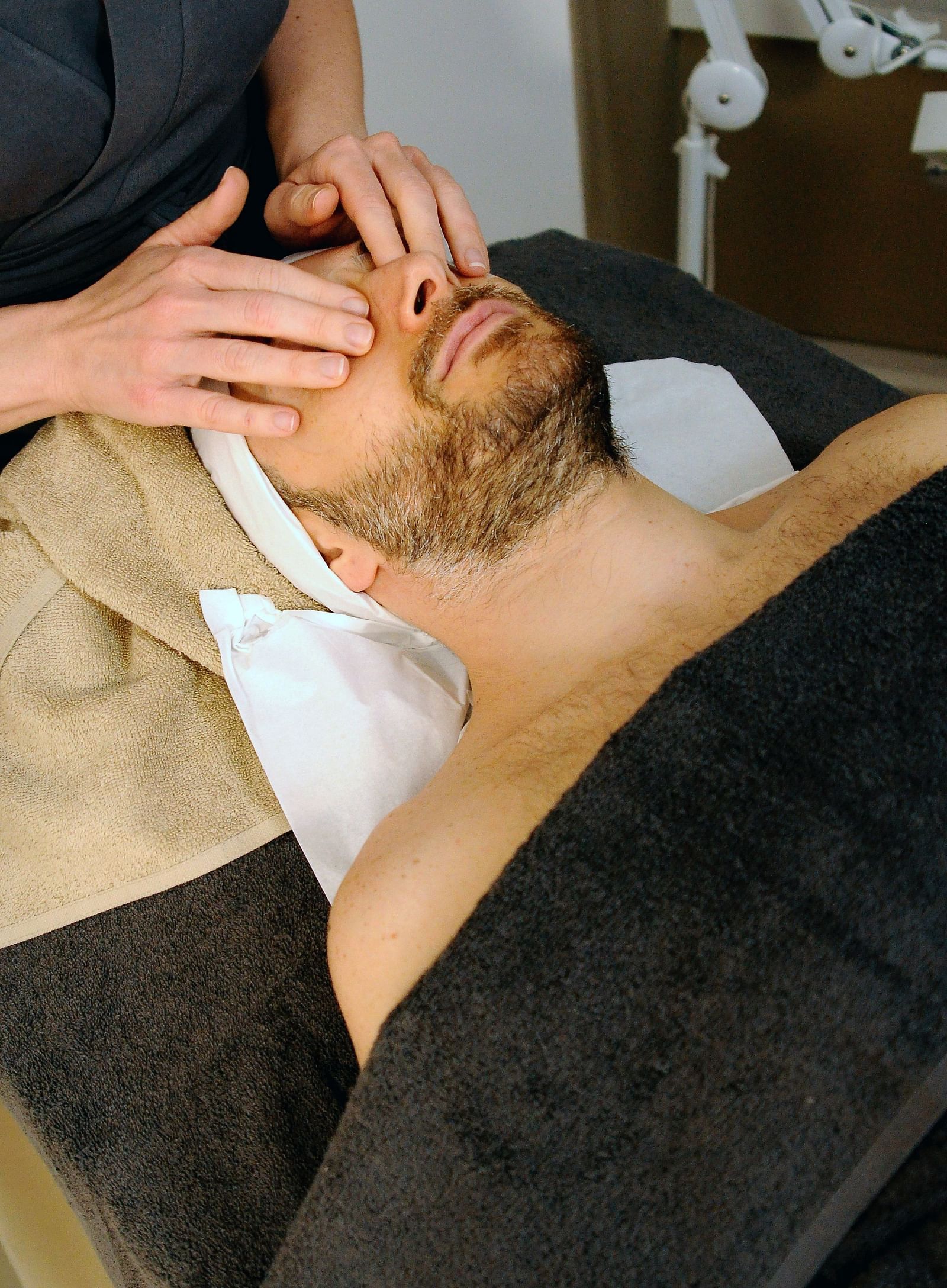 A man lying on the spa bed to get a face massage