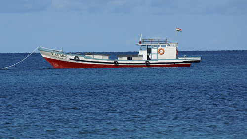 An overview of a solitary boat on the sea with blue sky in the background
