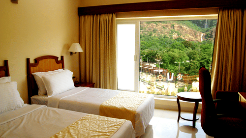 a twin bed with a study table in front of it inside a room at - Raj Park Hotel, Tirupati