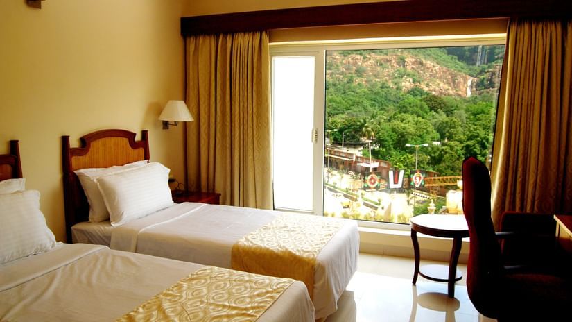 a twin bed with a study table in front of it inside a room at - Raj Park Hotel, Tirupati