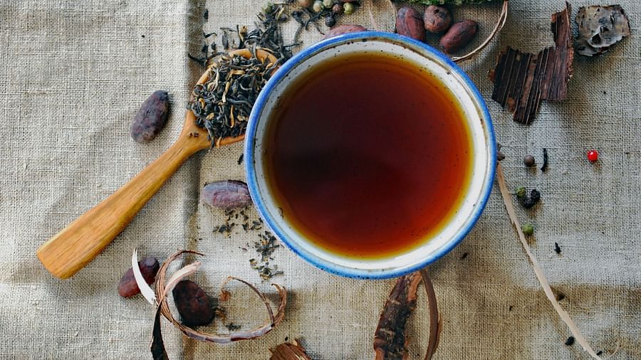A cup full of detoxing tea and some kind of spices on the spoon next to the cup