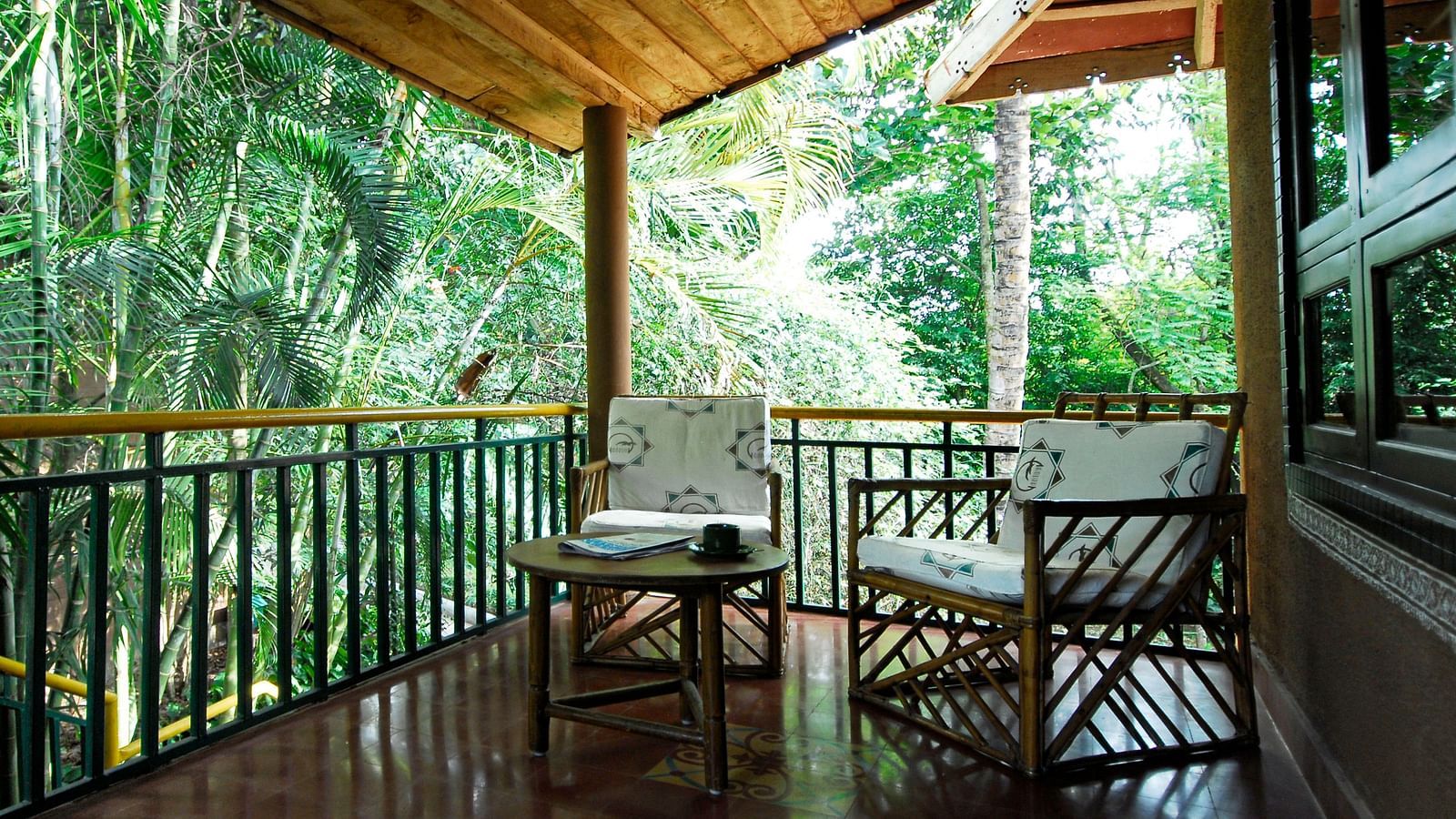 image of the outdoor seating area with lush green surroundings at the heritage premium rooms at hoysala village resort, hassan.