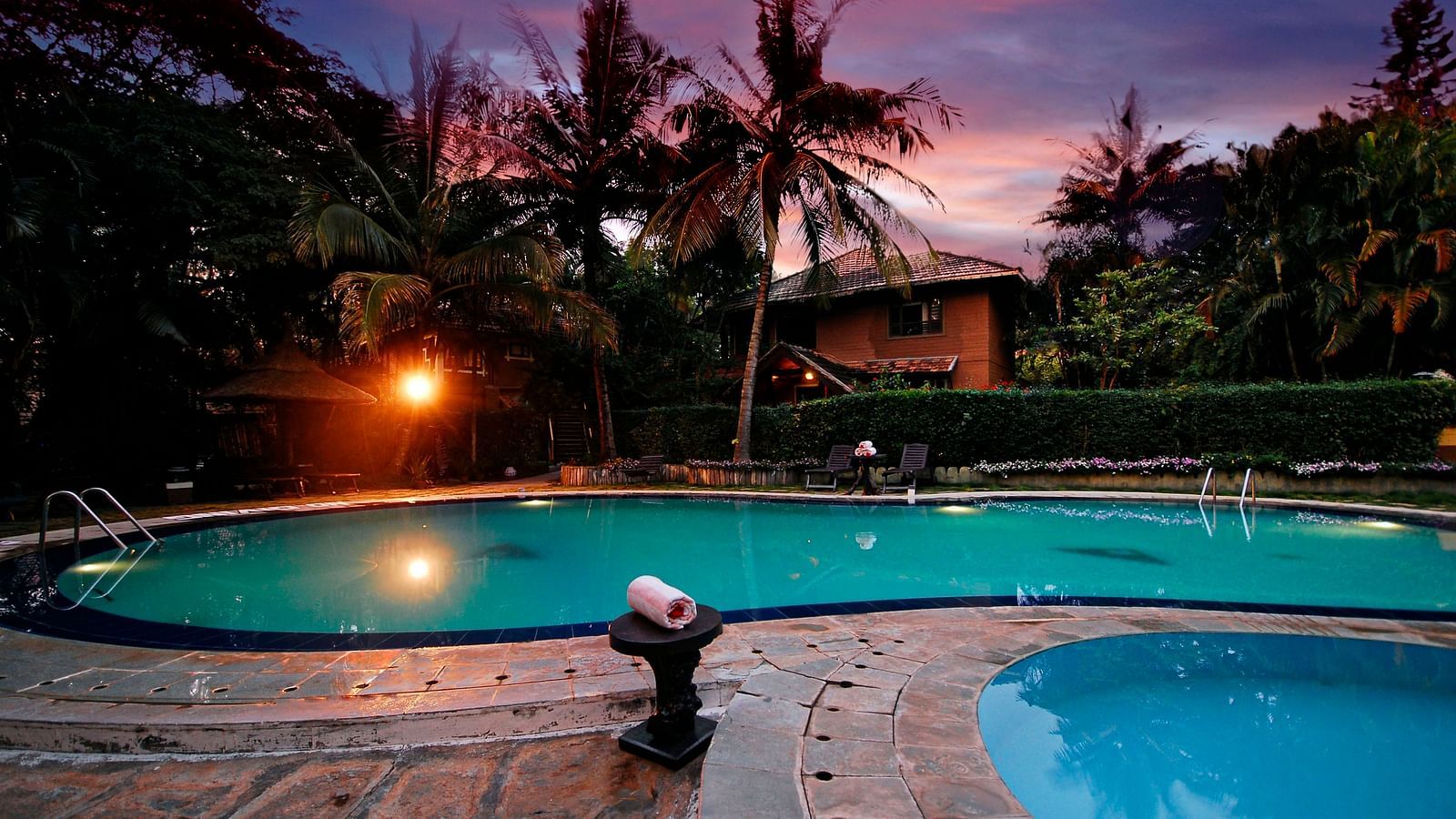 An overview of a swimming pool in the night - Hoysala Village Resort, Hassan.