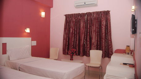 A spacious hotel bedroom accommodating 3 single beds, pink accent walls, and a window with dark curtains - Hotel Pandian