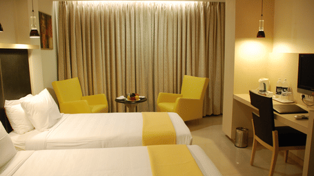 A room with twin beds and sitting area at The Oriental Residency.