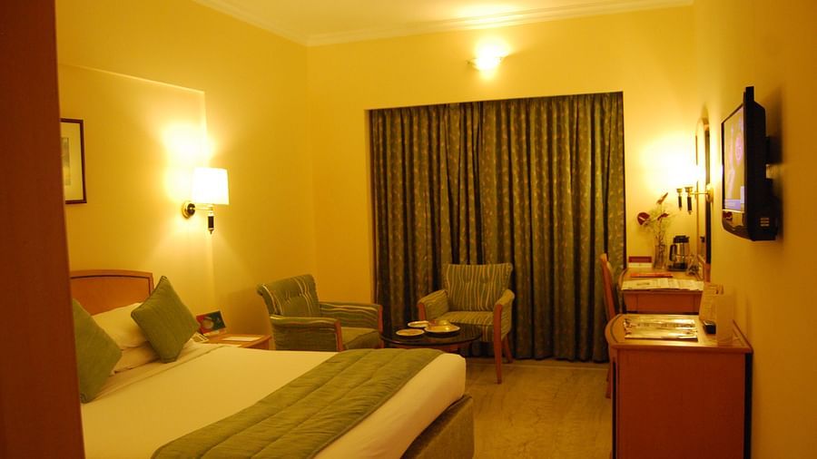 A photo showing a room with bright lights where a large bed, two chairs, and a flat screen TV are visible.