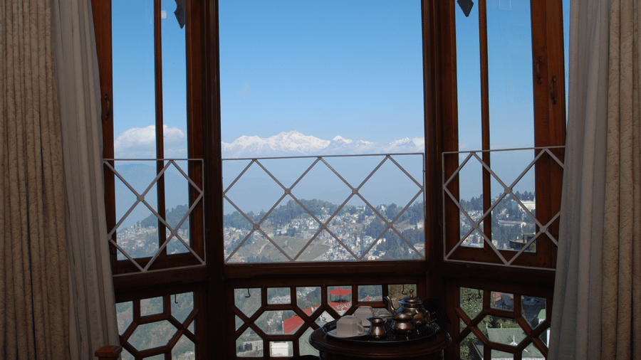 Large window view from the Executive Suite at Cedar Inn, showing mountain scenery and hillside surroundings framed by wooden window panels and curtains.