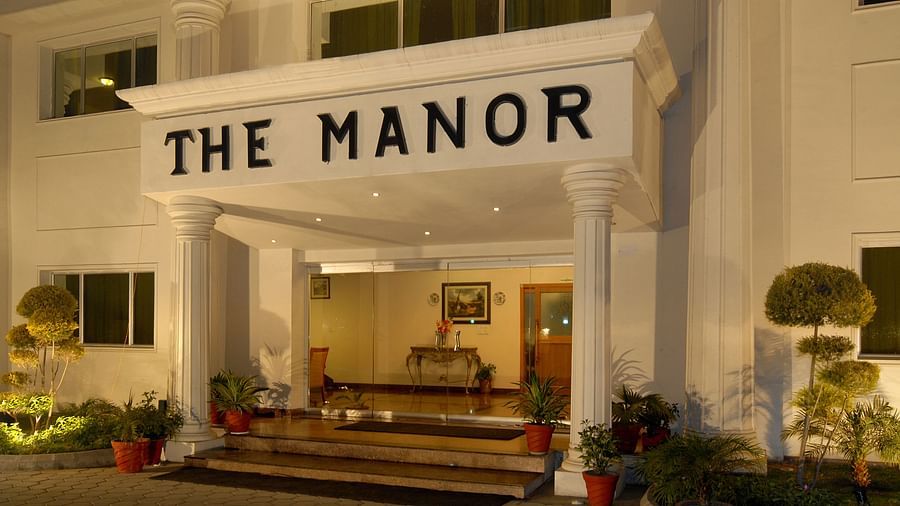 The facade of a hotel with small bushes on the sides and steps leading up to the entrance