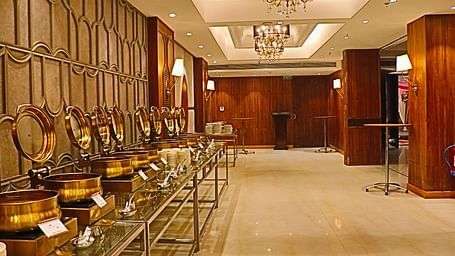 Buffet station with silver chafing dishes and ornate wall mirrors.