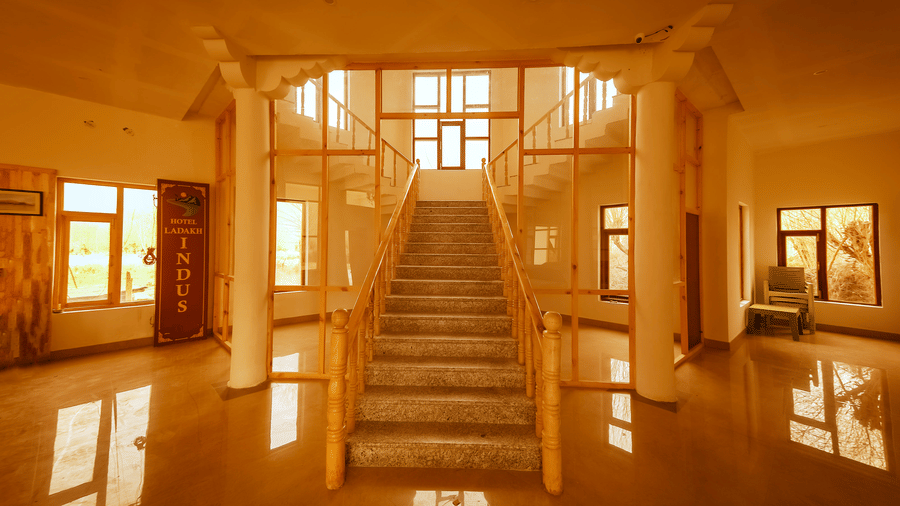 A grand wooden staircase leading upwards in a sun-drenched hallway at Indus Serenity Retreat.