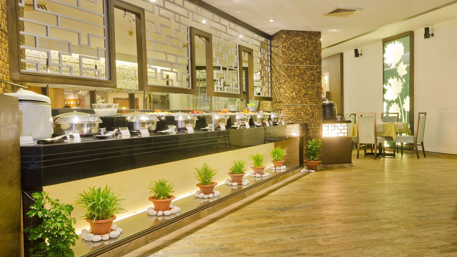 Buffet area decorated with potted plants and warm, welcoming lighting.