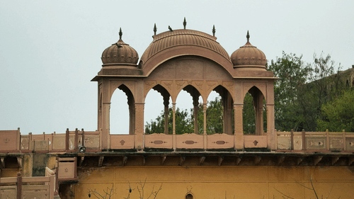 A traditional architectural structure with ornate arches, set against a misty sky.