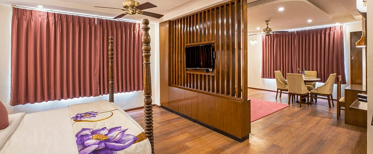 Full view shot of the Suite at Regenta Inn DLS with a wooden partition in the middle with a television mounted over it.