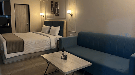 A bedroom at Urban Suites, Jaipur with a double bed, bedside lighting, wall art, and a seating area with a centre table.