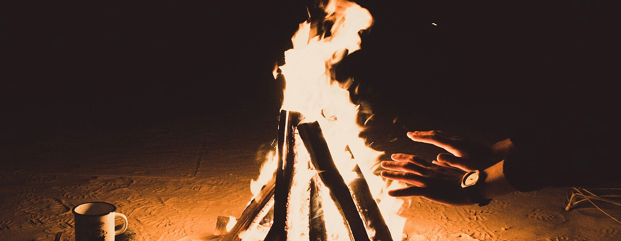 An image of a bonfire and people surrounding it