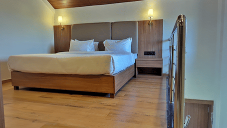 Bedroom with a double bed, wooden staircase, and glass railing.