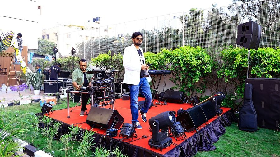 A performer on stage in an outdoor event setup with greenery and vibrant decor - Grand Continent, Brookefield