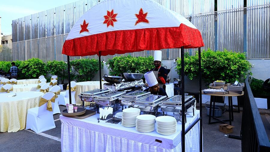 A buffet spread under a red canopy with seating arrangements in a lush outdoor venue - Grand Continent, Brookefield