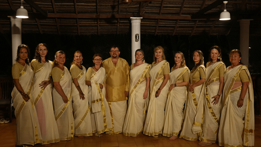 A group of people wearing traditional south Indian attire and posing for a picture at Ayur On The Beach Nattika.