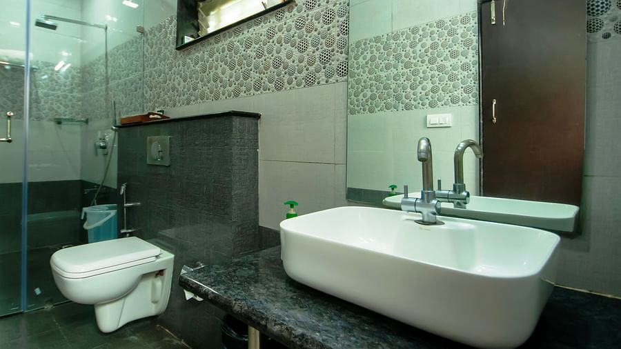 Image of a washroom with a sink, a toilet and a shower area separated by a glass wall at Coorg Jungle Camp Backwater Resort, Kushalnagar.