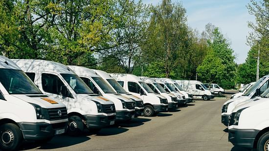 multiple white vans parked in a row