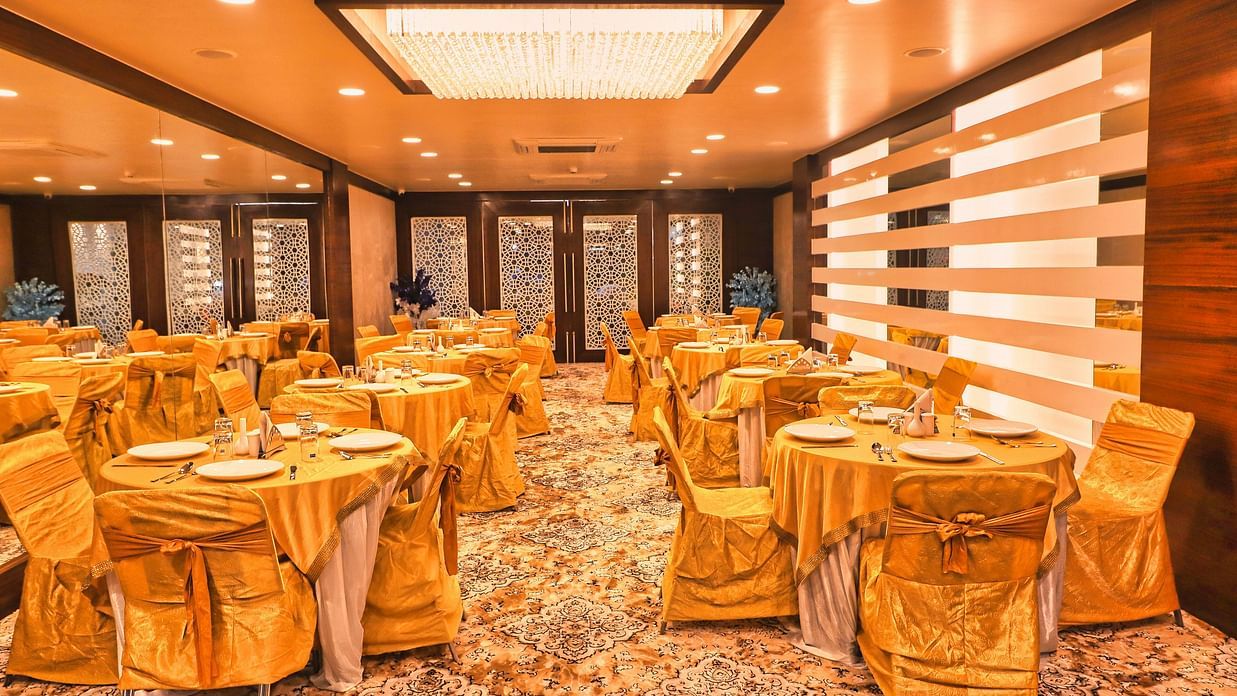 Image of a banquet hall with tables and chairs with lights on the ceiling at Clarks Inn Express, Udaipur.
