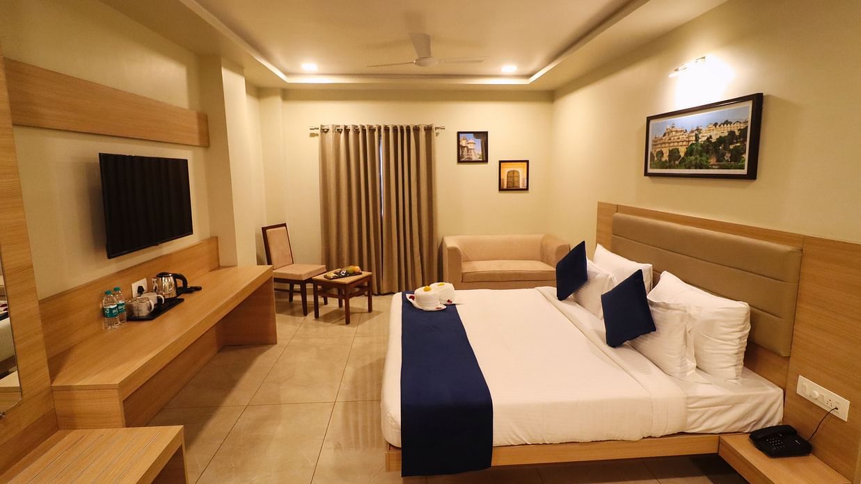 Image of Premium Room with a bed, television in front and a photo frame above the bed at Clarks Inn Express, Udaipur.