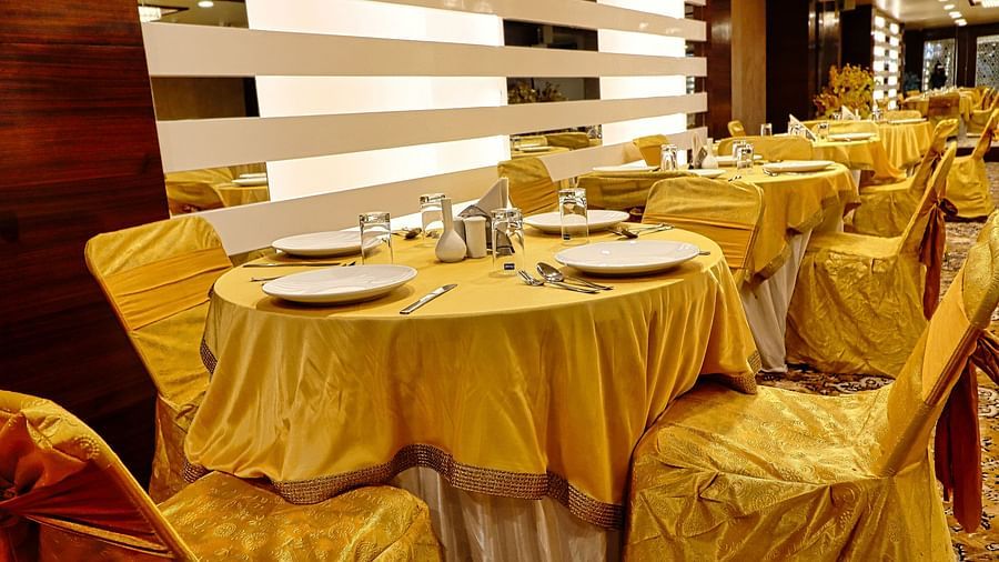 Image of a banquet hall with round tables and chairs around it at Clarks Inn Express, Udaipur.