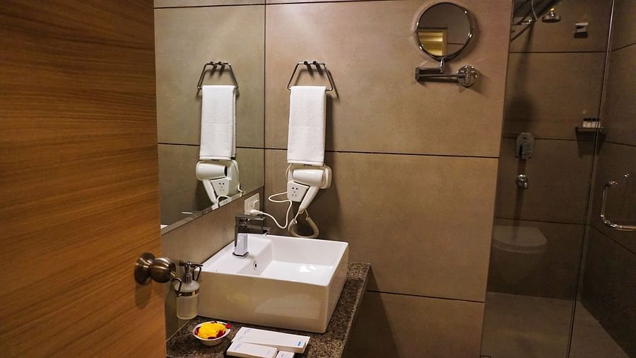 Image of the washroom at Deluxe Room with a sink and  towels above it at Clarks Inn Express, Udaipur.