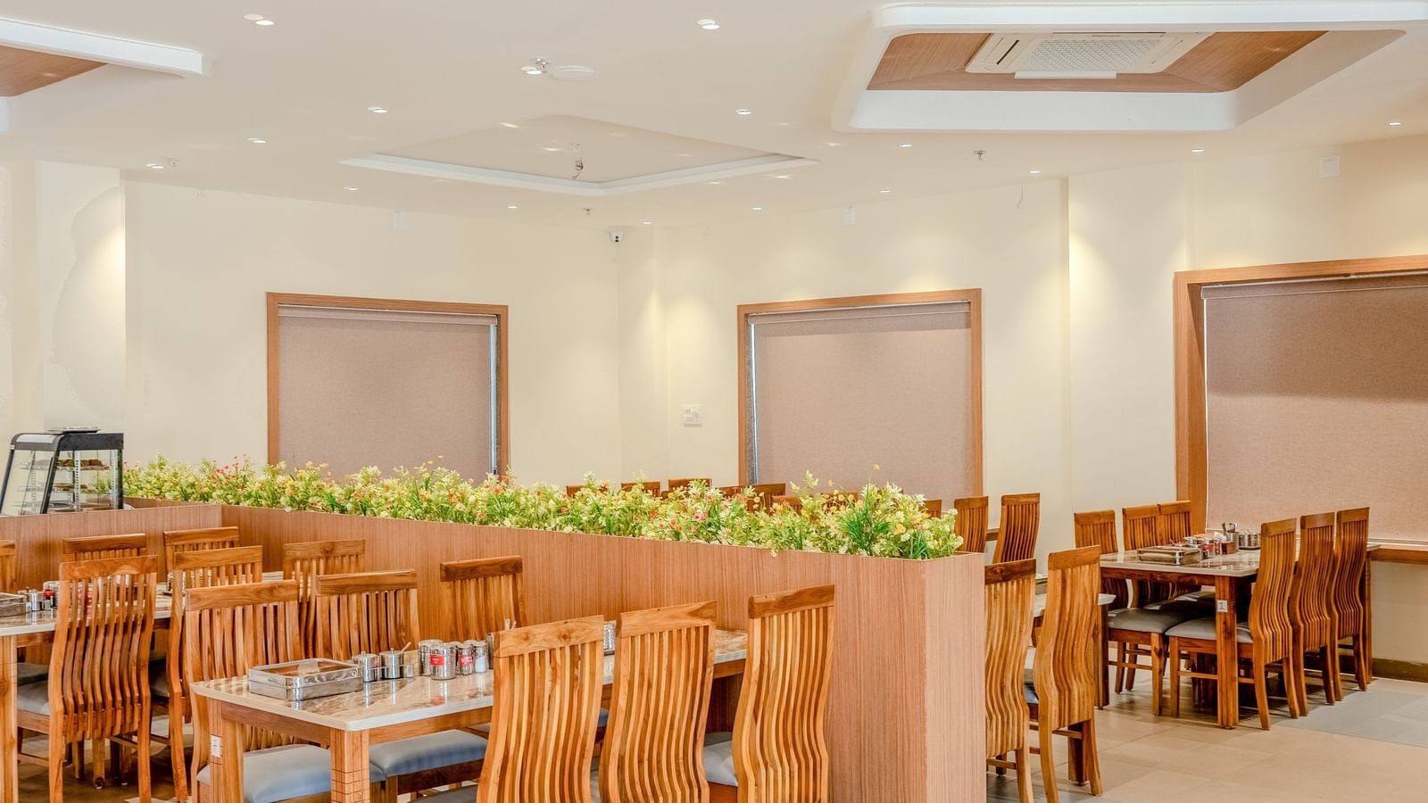 A brightly-lit dining area at Daksh The Grand Goverdhan, Dwarka, featuring centralised air-conditioner.