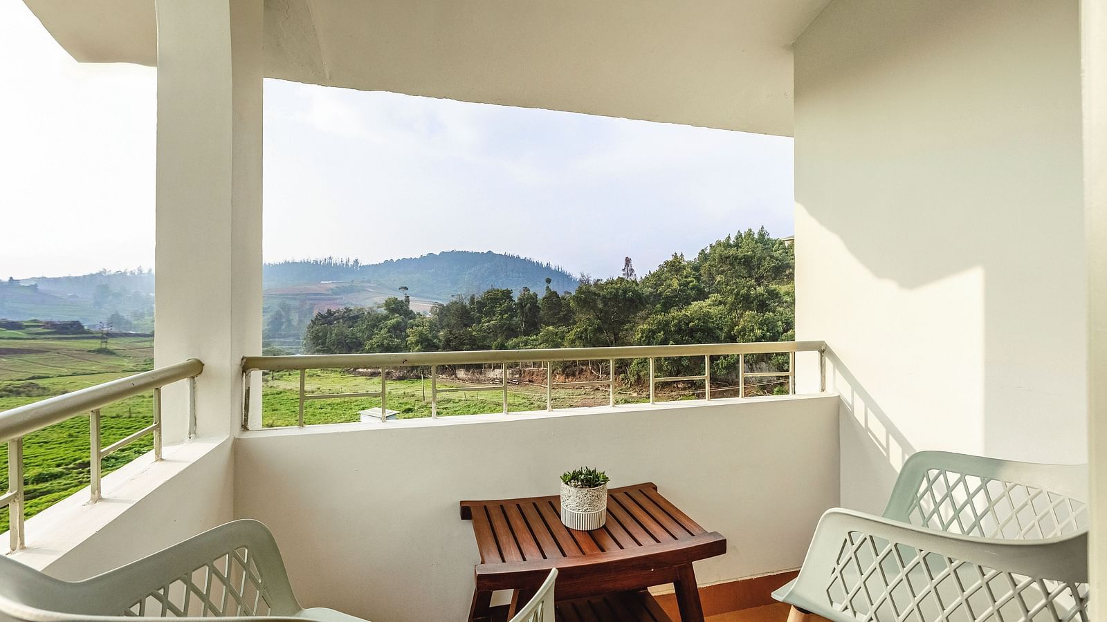 Balcony at Mango Hill Shola, Ooty, furnished with outdoor seating and a table, overlooking a peaceful landscape