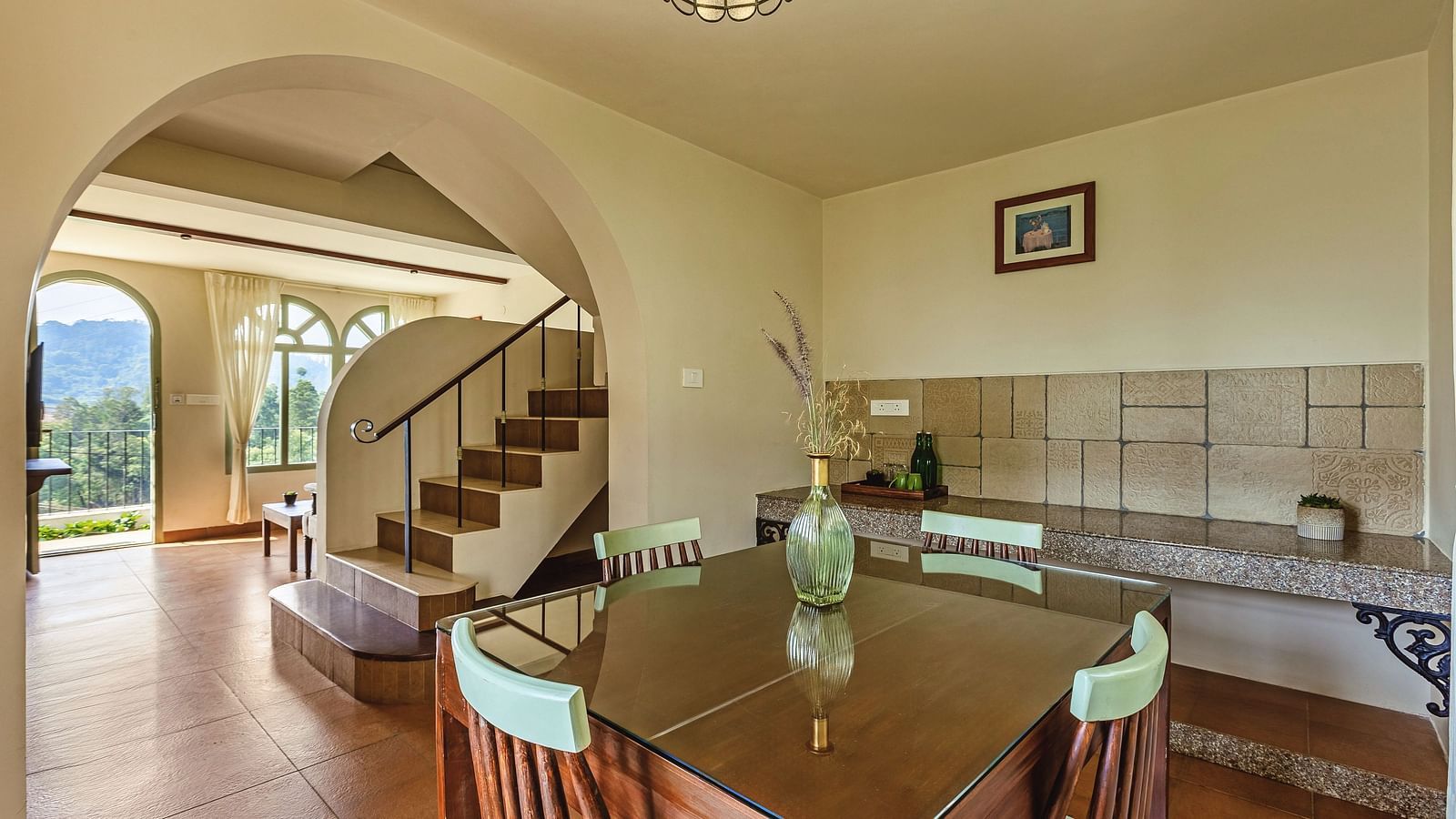 Spacious open-plan living and dining area at Mango Hill Shola, Ooty, with tiled flooring, classic furnishings, and a staircase leading to the upper level.