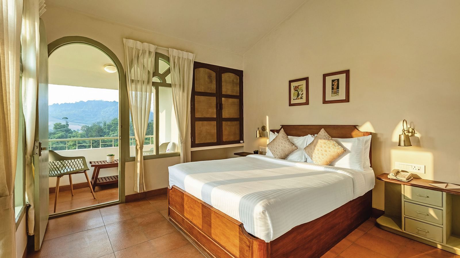 Bedroom at Mango Hill Shola, Ooty, with a double bed, wooden flooring, and an arched window offering an outdoor view.