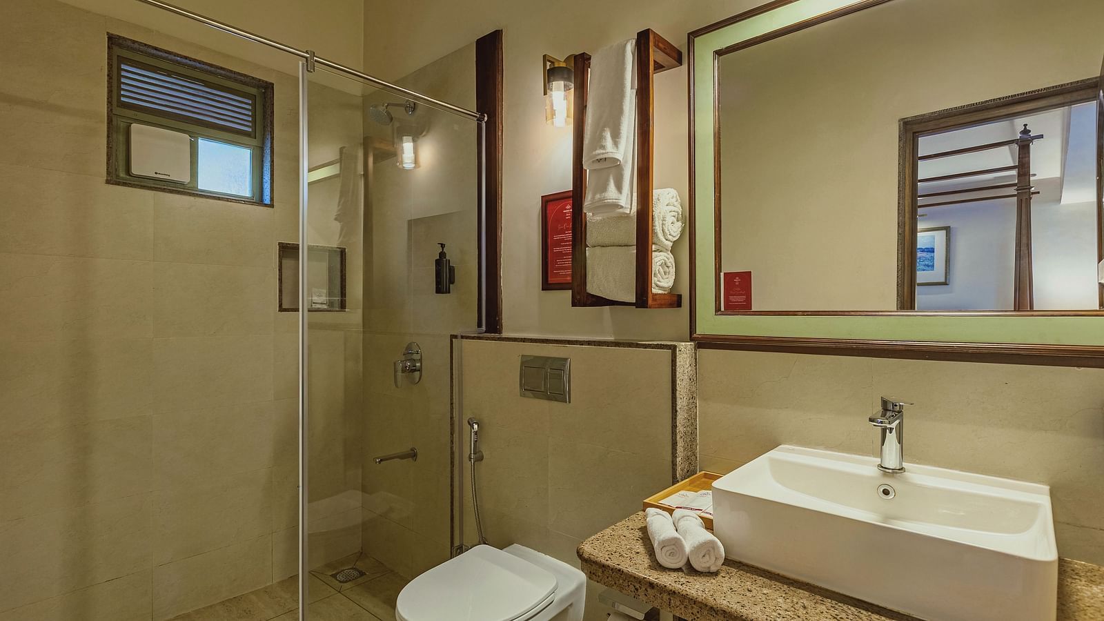 Contemporary bathroom at Mango Hill Shola, Ooty showcasing a wide mirror, clean countertop, and walk-in glass shower.