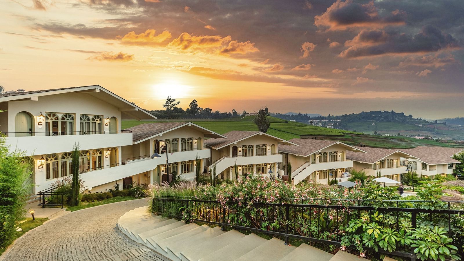 Walkway weaving through Mango Hill Shola, Ooty, flanked by resort buildings and landscaped surroundings.