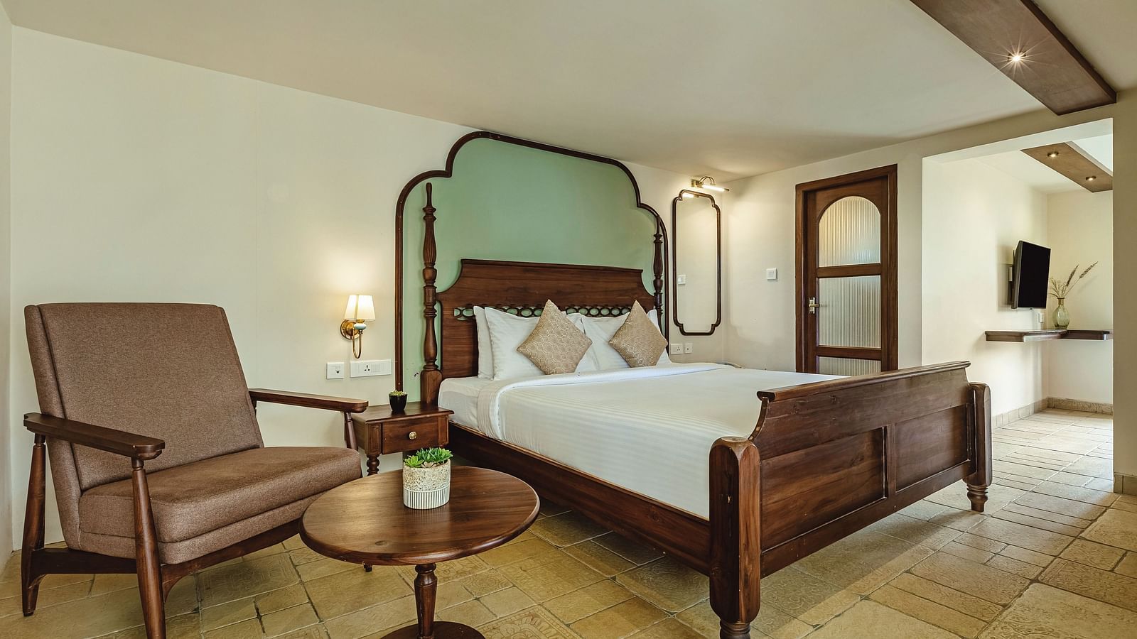Charming bedroom at Mango Hill Shola, Ooty with classic wooden furniture, armchairs, and soft ambient lighting.
