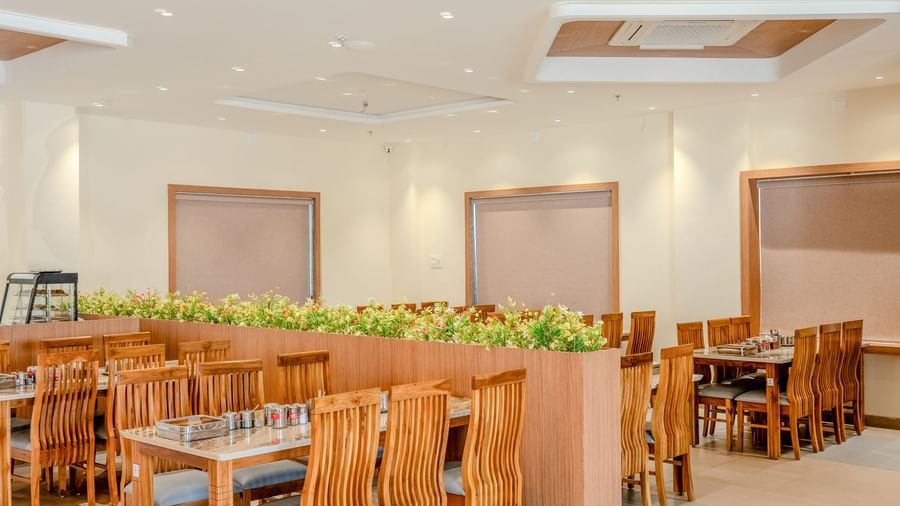 A brightly-lit dining area at Daksh The Grand Goverdhan, Dwarka, featuring centralised air-conditioner.