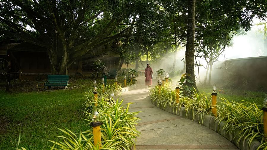 a pathway amidst the green garden at hoysala village resort, hassan