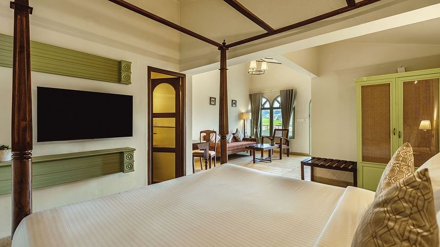 A four-poster bed in a well-lit bedroom at Mango Hill Shola, Ooty, with a large TV and tasteful interior design.