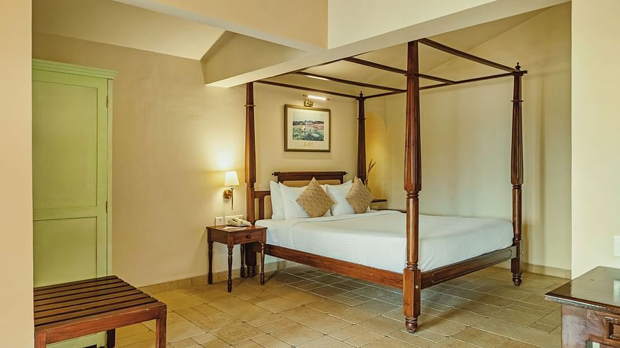 A bedroom at Mango Hill Shola, Ooty featuring a four-poster bed, wooden bench, and soothing lighting