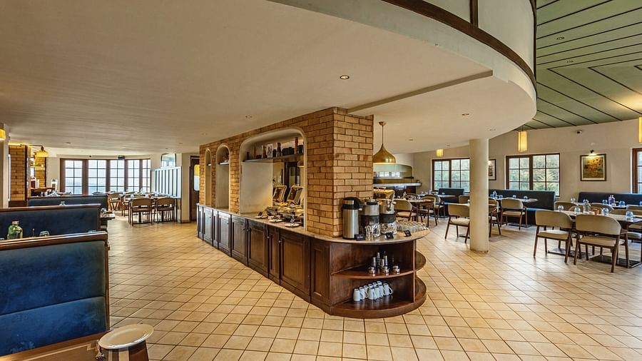 Curved dining counter and coffee station at Mango Hill Shola, Ooty with cosy booth seating and large windows creating a relaxed ambiance.