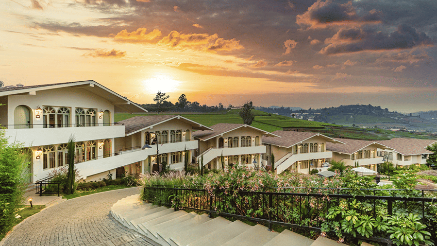 Walkway weaving through Mango Hill Shola, Ooty, flanked by resort buildings and landscaped surroundings.
