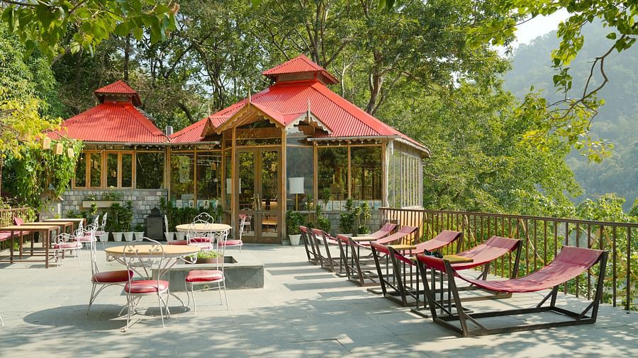 An outdoor gazebo with lounge chairs, overlooking a valley with trees and mountains.