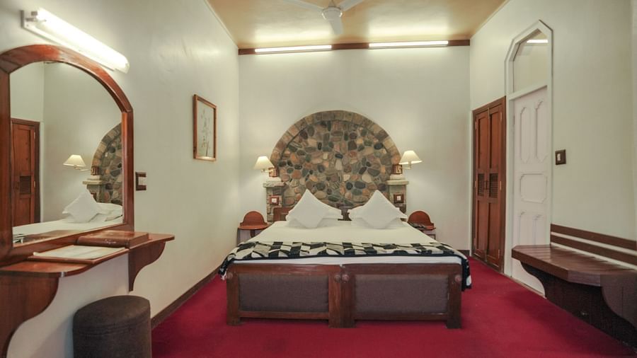 A bedroom with a bed, a rug, and warm lighting, interior setting - The Den Corbett Resort & Spa, Kumeria.