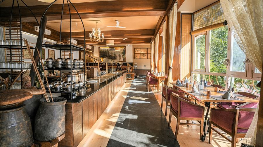 A restaurant interior with a bar, tables, and chairs, warm lighting.
