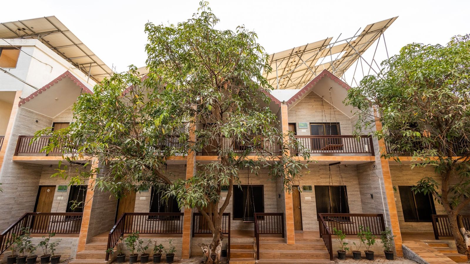The facade of Daksh Resort & Amusement Park, Sasan Gir featuring the sloped roofs multi-storey building surrounded by greenery.