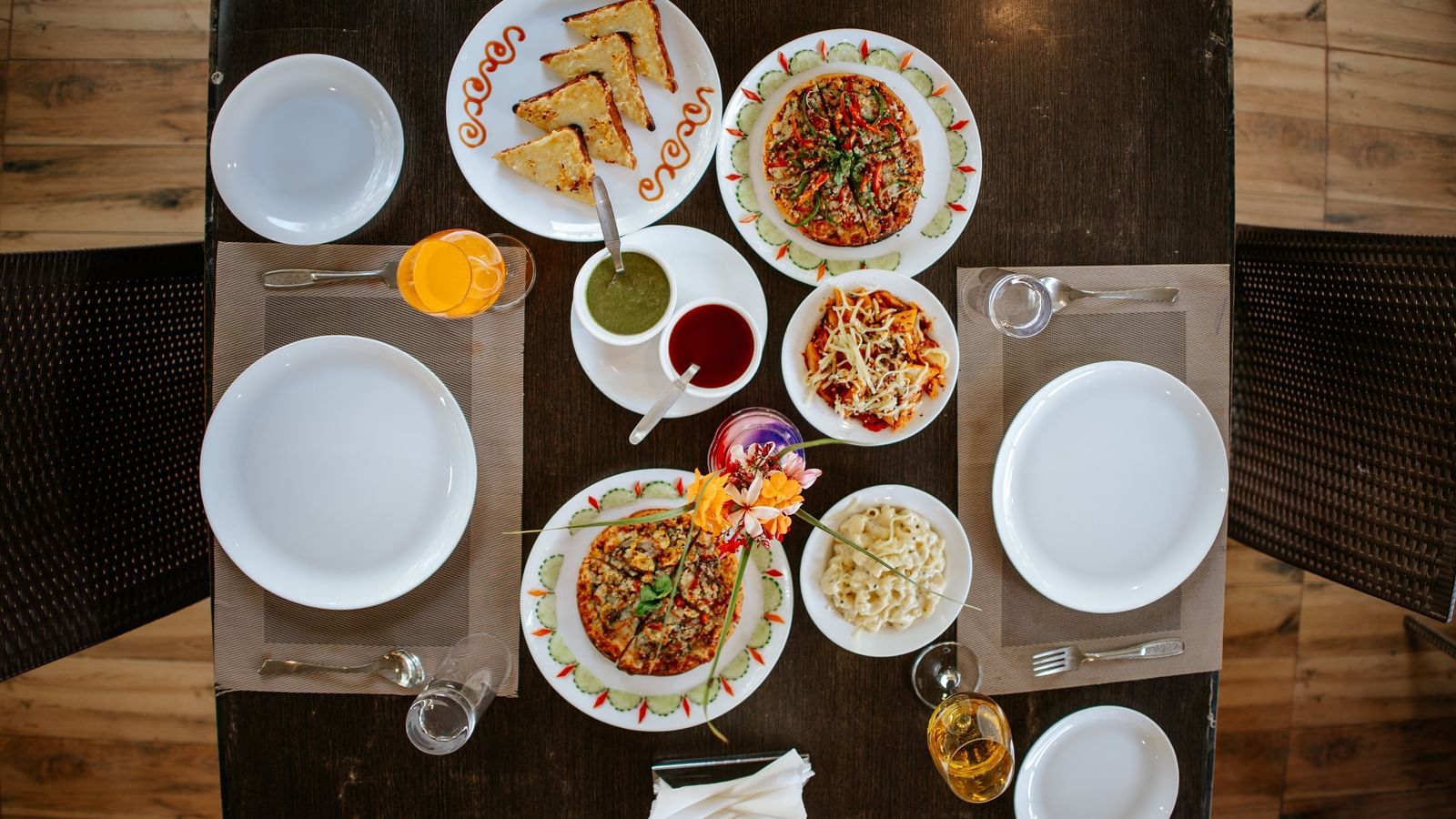 An overhead shot of a dark table set with 6 plates of various Indian snacks and flatbreads, at Daksh Resort & Amusement Park, Sasan Gir.