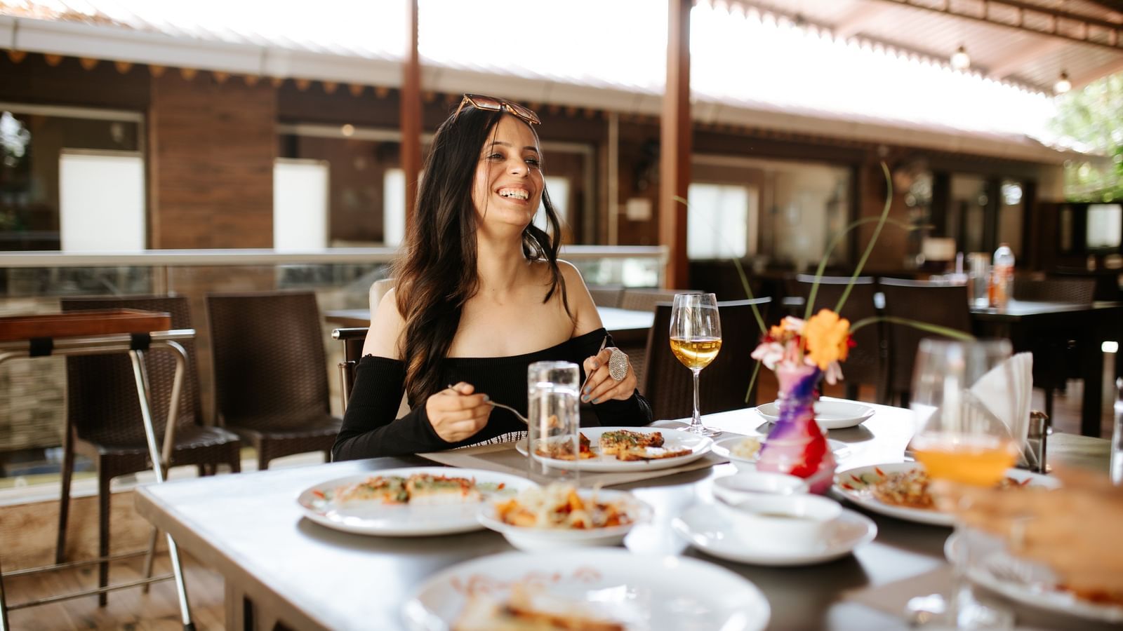 2 women seated at an outdoor restaurant table with plates of food, at Daksh Resort & Amusement Park, Sasan Gir.